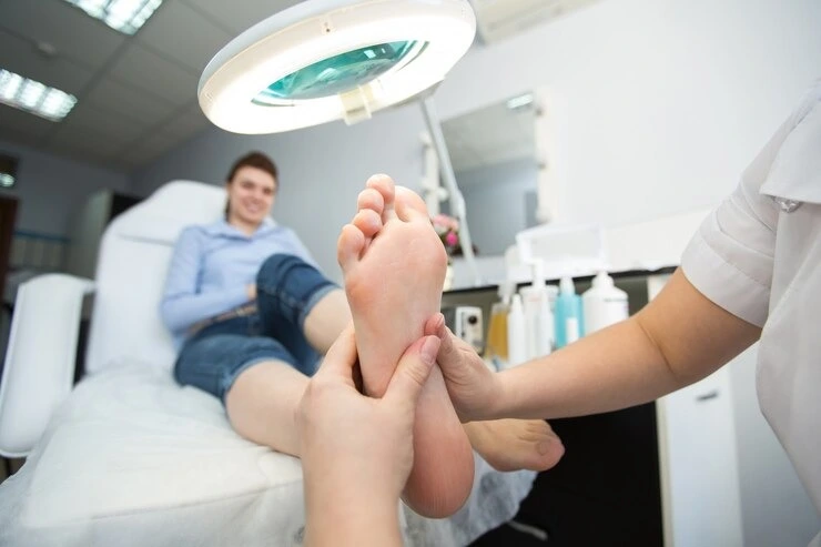 Specialist conducting physical foot examination with seated patient at Precision Podiatry clinic in Alma, MI